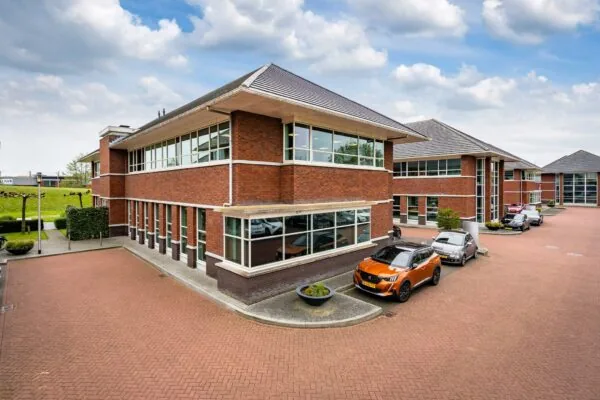 Modern kantoorpand aan de 1e Barendrechtseweg met omliggende parkeerplaatsen en geparkeerde auto's.